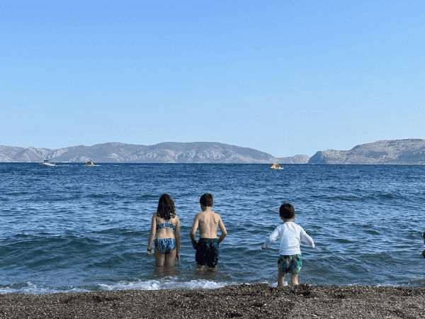 Three children playing at Ocean City beach with mountains in the background.