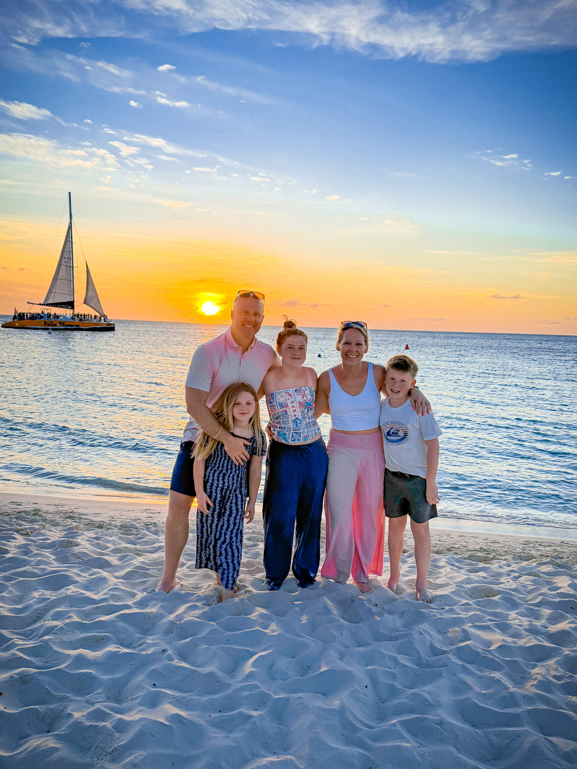 Family enjoying sunset on Ocean City beach with sailboat in background.